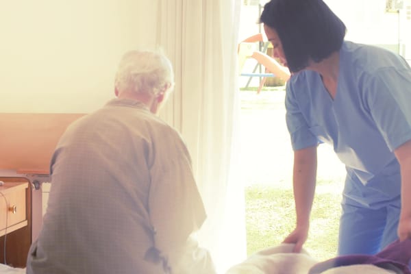 A caregiver assisting a senior resident in a room