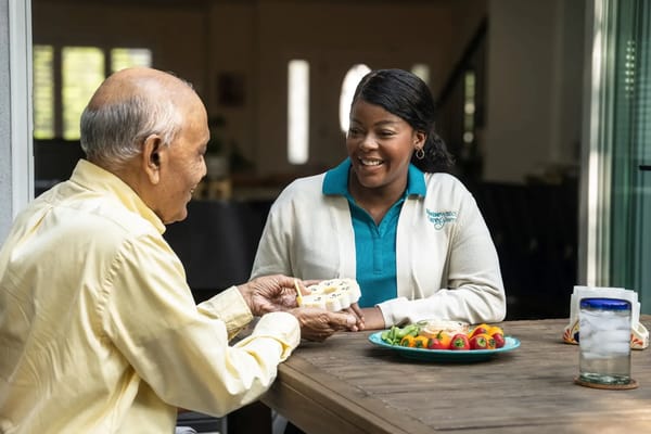 A caregiver interacting with a senior over a meal