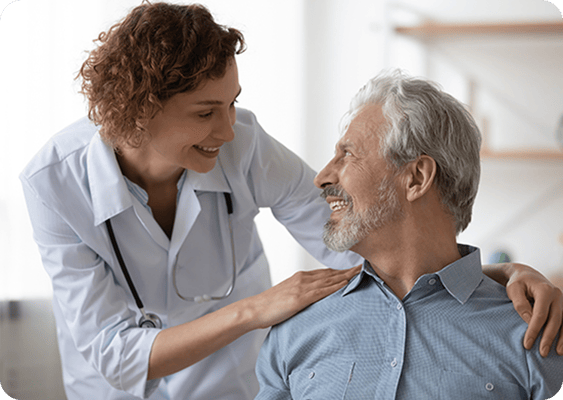 A caregiver smiles at a senior resident indoors