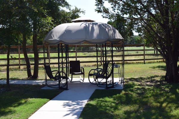 Outdoor gazebo with rocking chairs in a grassy area