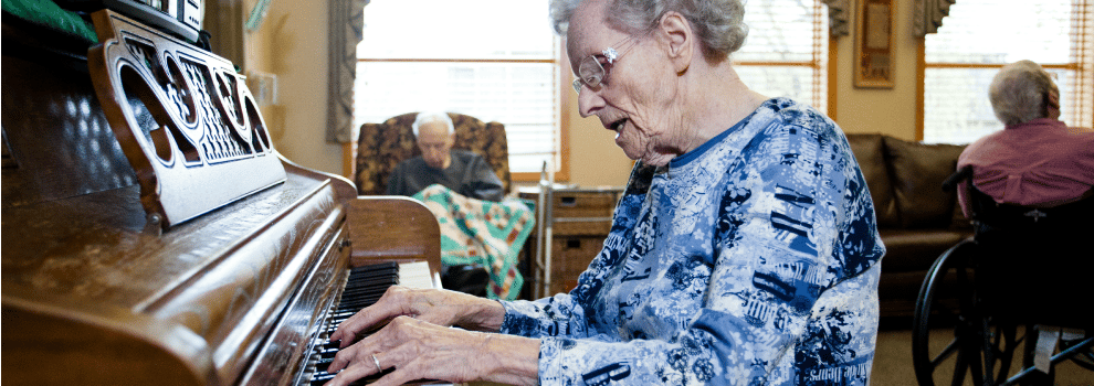 Resident playing piano in a cozy common area
