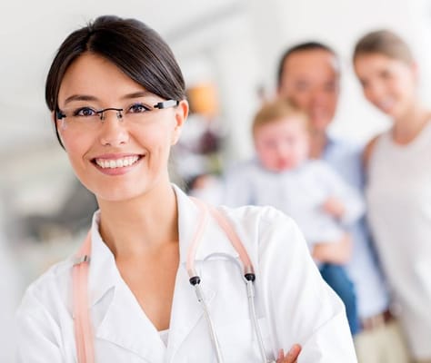 A smiling healthcare professional with a family in the background