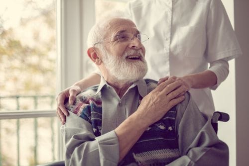 Smiling elderly man with caregiver in a cozy environment