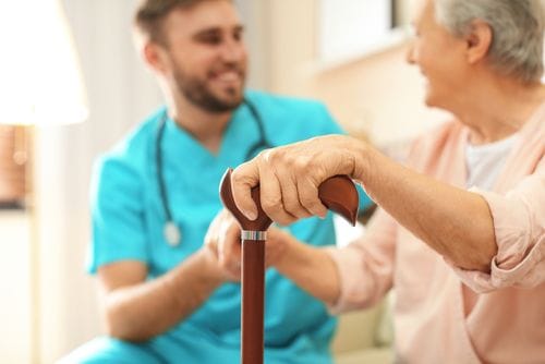 Staff assisting a resident with a cane