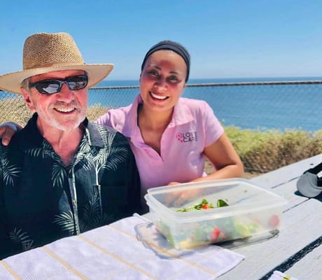Outdoor dining scene with a resident and staff member