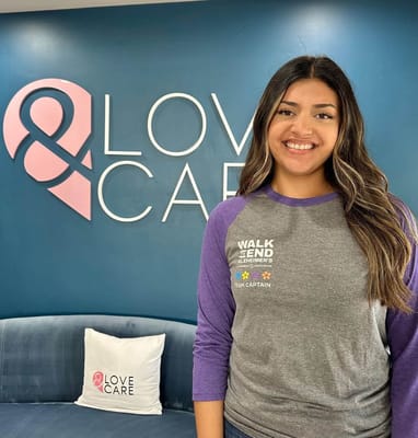 Staff member posing in front of the facility logo