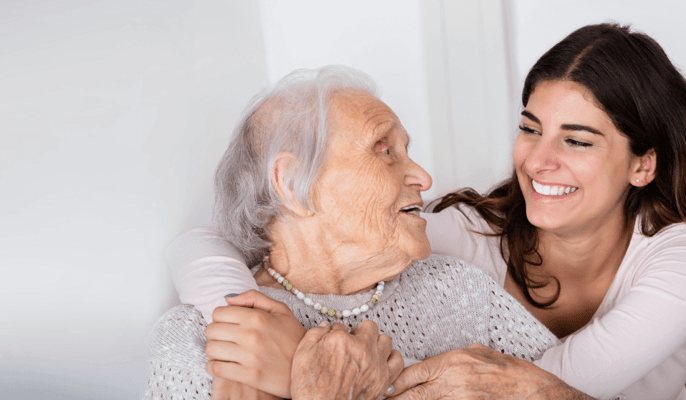 An older woman smiling at a younger caregiver