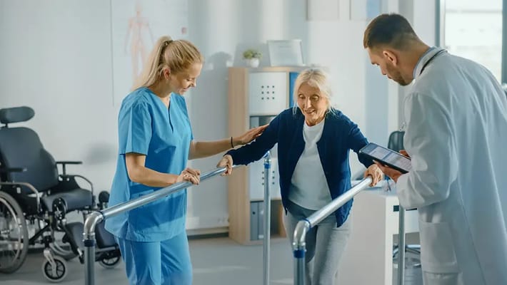 Healthcare staff assisting senior woman with walking aid