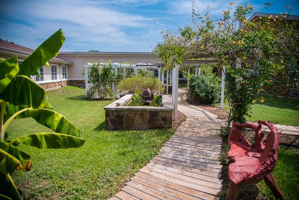 Garden pathway with greenery and sculpture.
