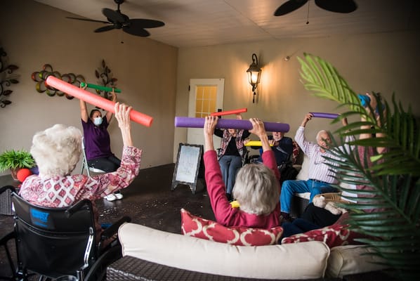 Residents participating in a group activity with pool noodles