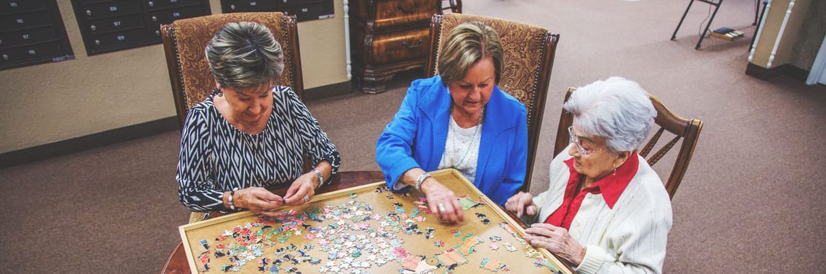 Residents and staff working on a puzzle together