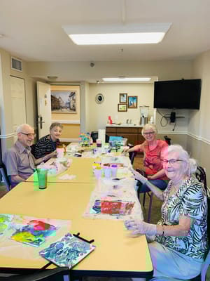 Residents engaged in a painting activity at a table