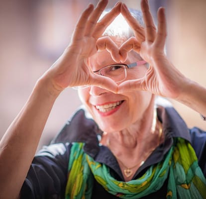 A smiling resident forming a heart shape with hands