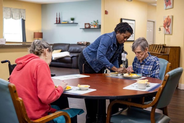 Staff serving food to residents in a dining area
