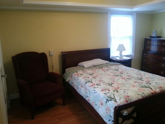 A cozy resident room with a bed and armchair