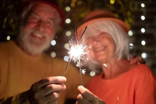 Two seniors celebrating with sparklers at a party