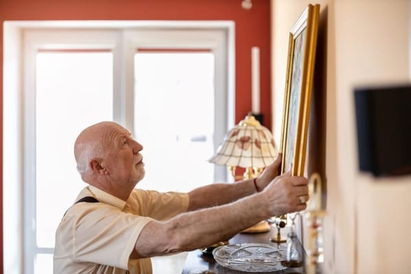 Senior man adjusting a picture frame indoors