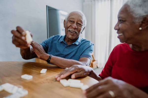 Two seniors playing dominoes at a table