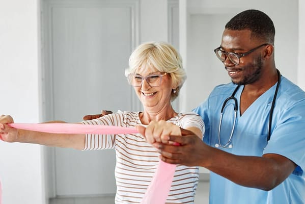 Resident engaging in stretching exercises with staff assistance