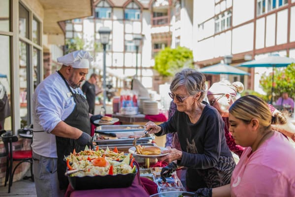 Residents enjoying a meal outside with staff serving food