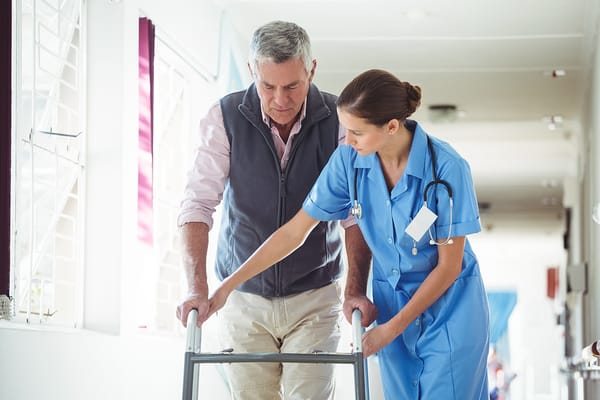 Nurse assisting resident with a walker in a hallway