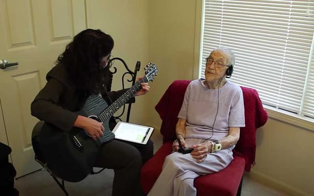 Therapist playing guitar for a resident