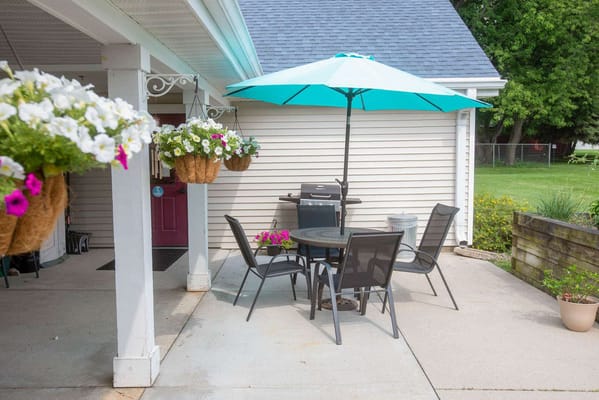 Outdoor patio area with table and chairs beneath an umbrella