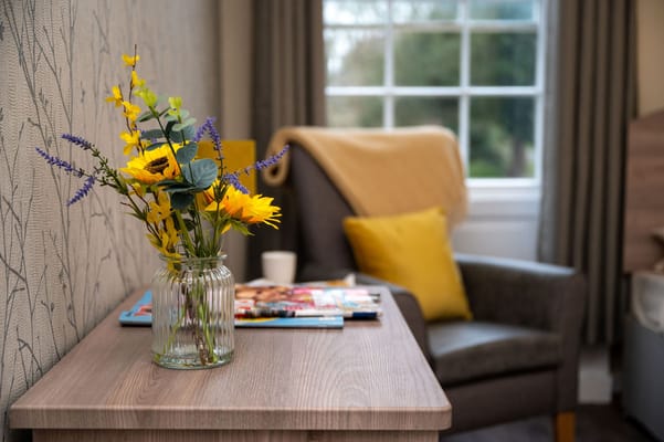 Cozy corner with flowers and a chair in a resident room