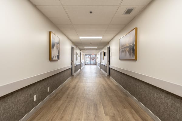 A well-lit hallway in the nursing home with artwork on the walls