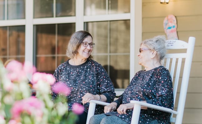 Two residents enjoying conversation on a porch
