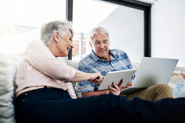 Two seniors engaged with digital devices in a cozy setting
