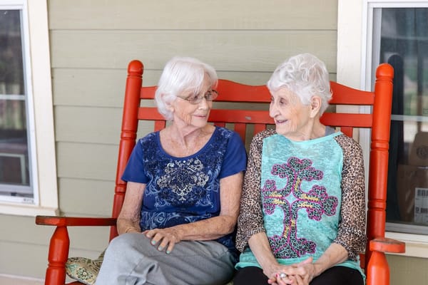 Two elderly women chatting on a porch