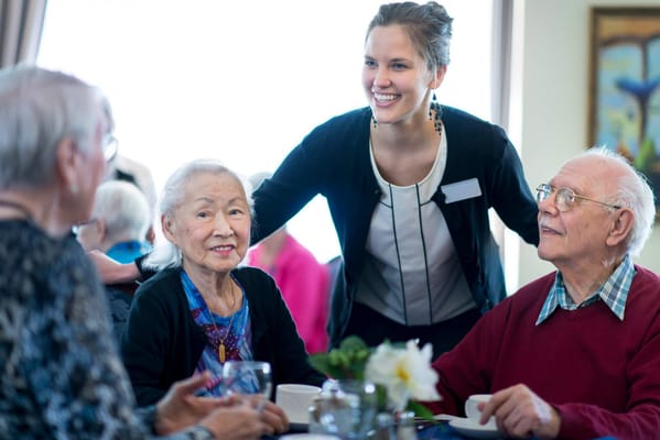 Residents enjoying a meal with staff in a dining area