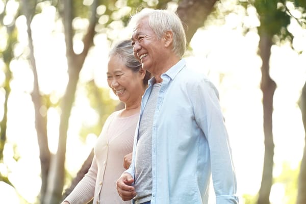 Older couple walking together outdoors, smiling