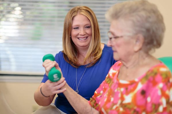 A staff member assisting a resident with weights