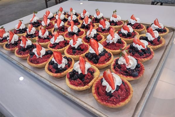 A display of berry tart desserts with whipped cream