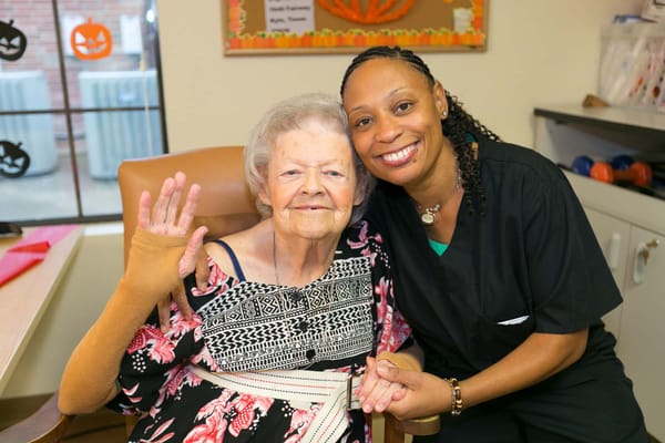 Staff member and resident smiling together in bright interior
