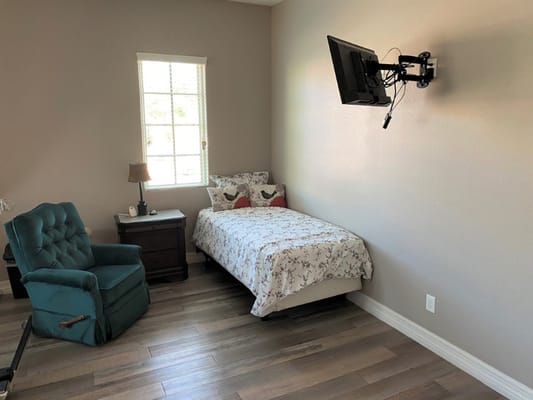 A private resident room with a bed and chair