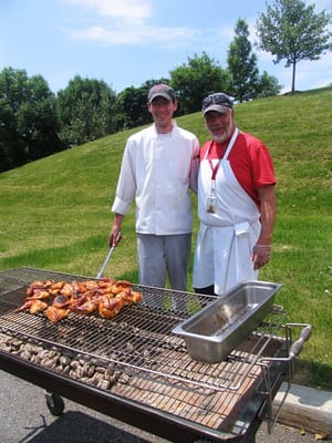 Two staff members grilling food outdoors