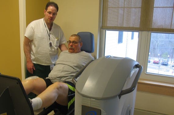 Resident exercising with staff assistance in therapy room