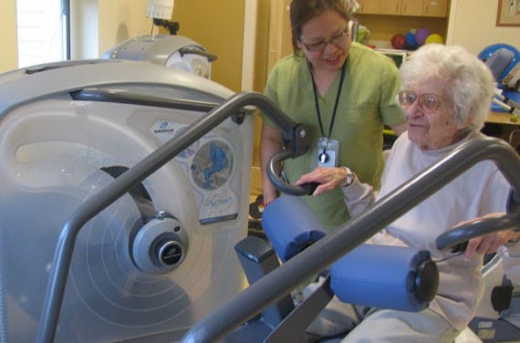 A resident exercising with staff assistance in an interior setting