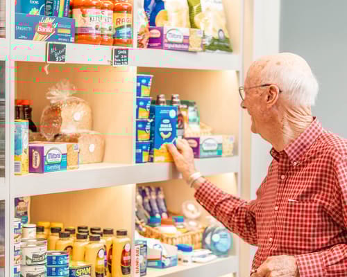 An elderly man browsing items on a pantry shelf