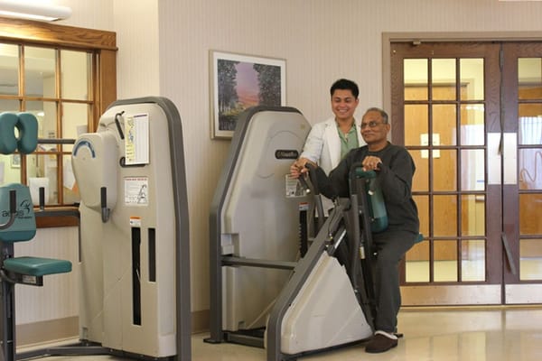 Staff assisting a resident with exercise equipment