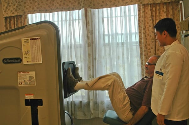 A staff member assisting a resident with leg press exercise equipment