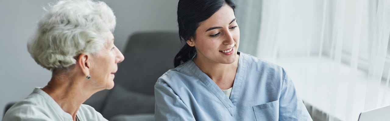 Caregiver assisting a resident in a bright indoor space