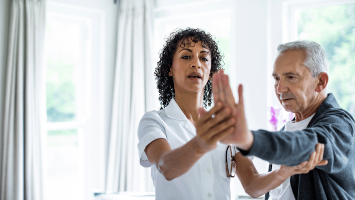 A caregiver assisting a senior resident in physical therapy.