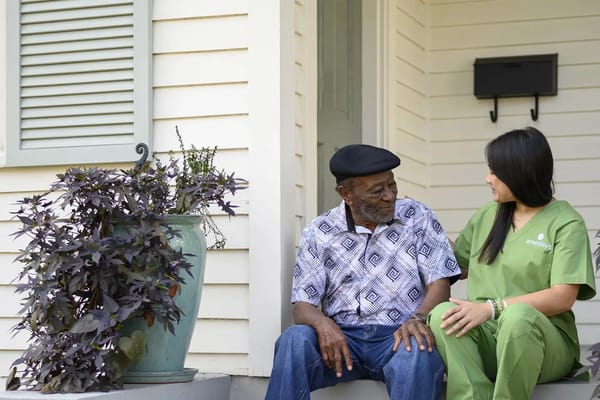 A resident and caregiver chatting on a porch