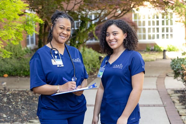 Two healthcare staff smiling in a garden area