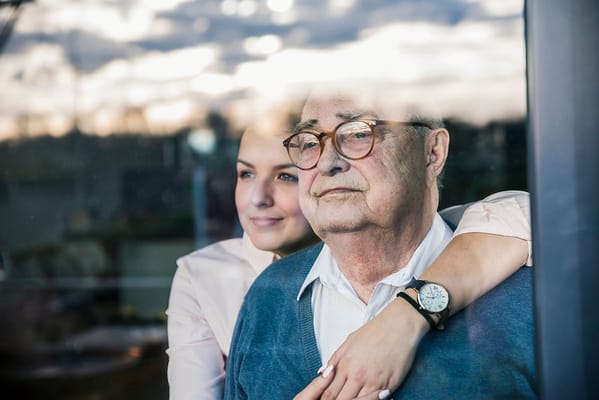 Elderly man and caregiver looking out a window