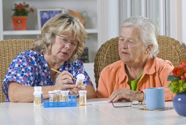 Staff assisting a resident with medication at a table